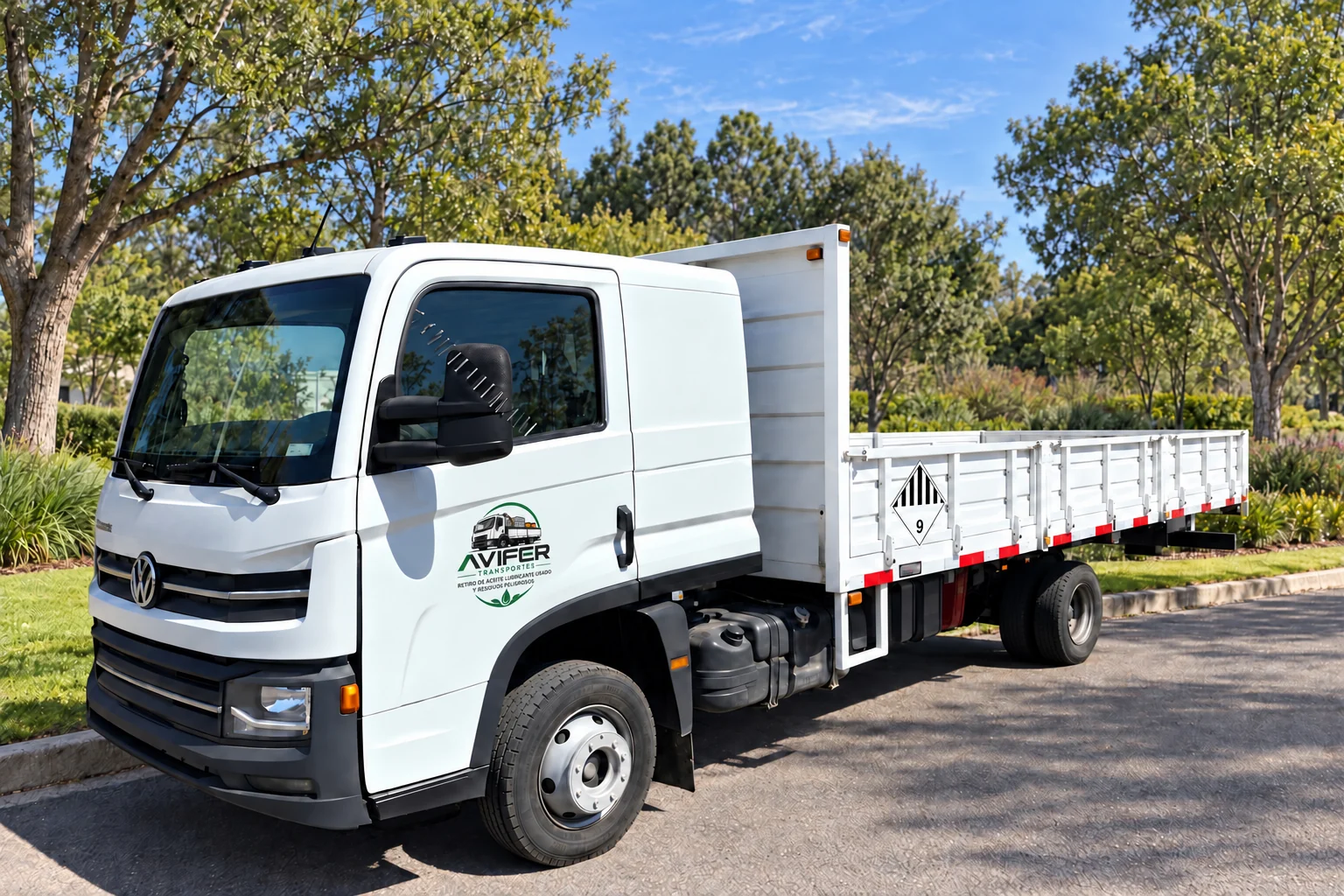 Volkswagen Delivery blanco con carrocería con baranda y logo AVIFER reducido en la puerta, en un área verde